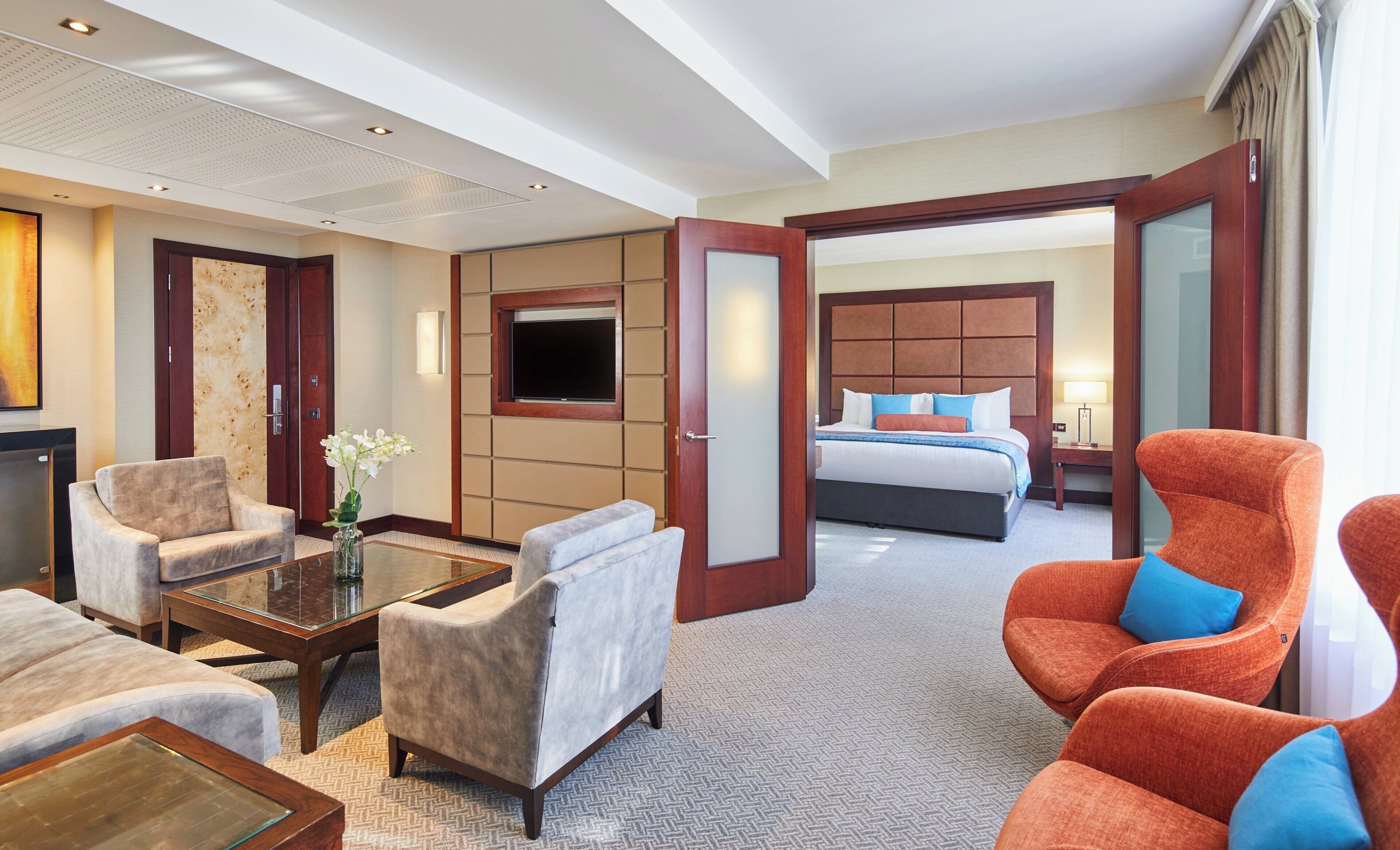 Une chambre d’hôtel avec un grand lit, deux fauteuils, un canapé, une table basse et un téléviseur.