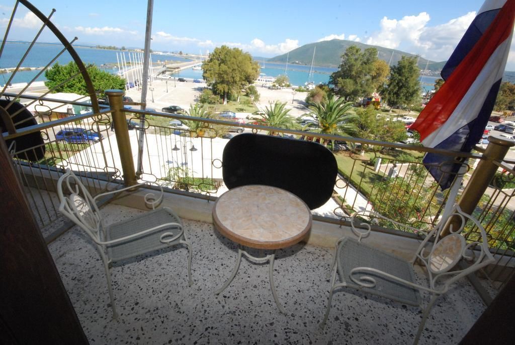 A balcony with a round table and two chairs, overlooking a beach and marina with boats.