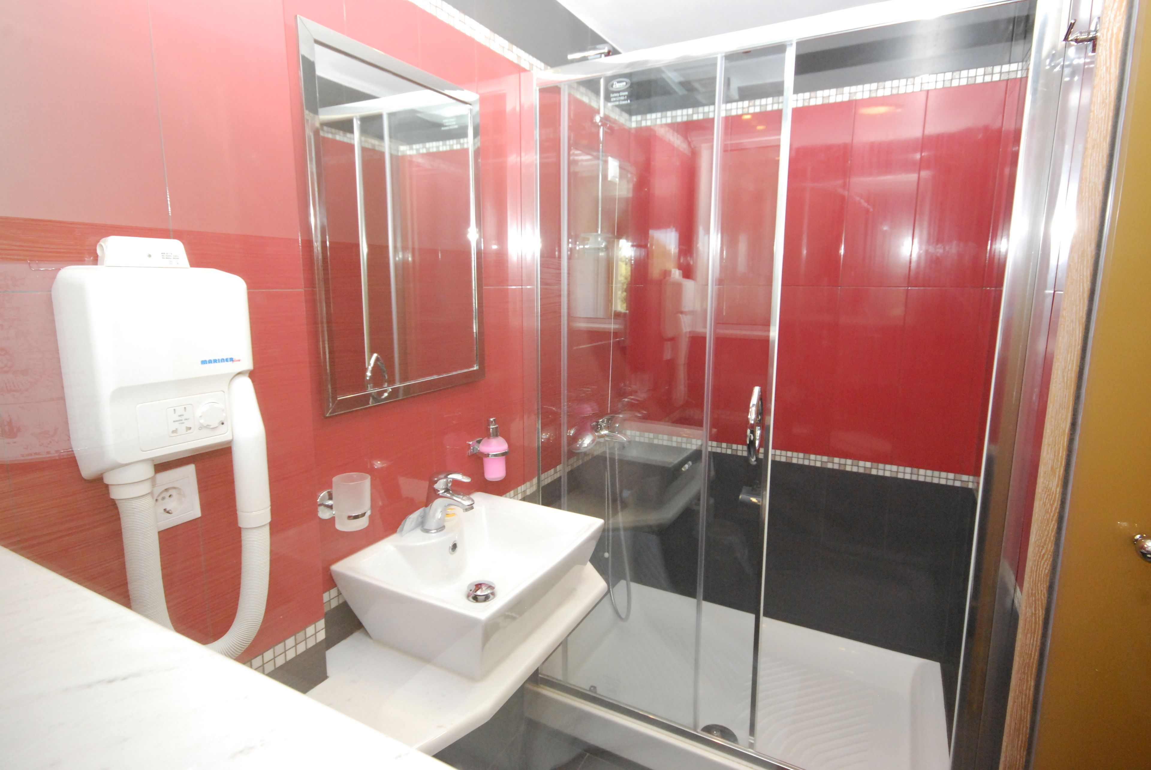A bathroom with a glass-enclosed shower, a sink, and a mirror.