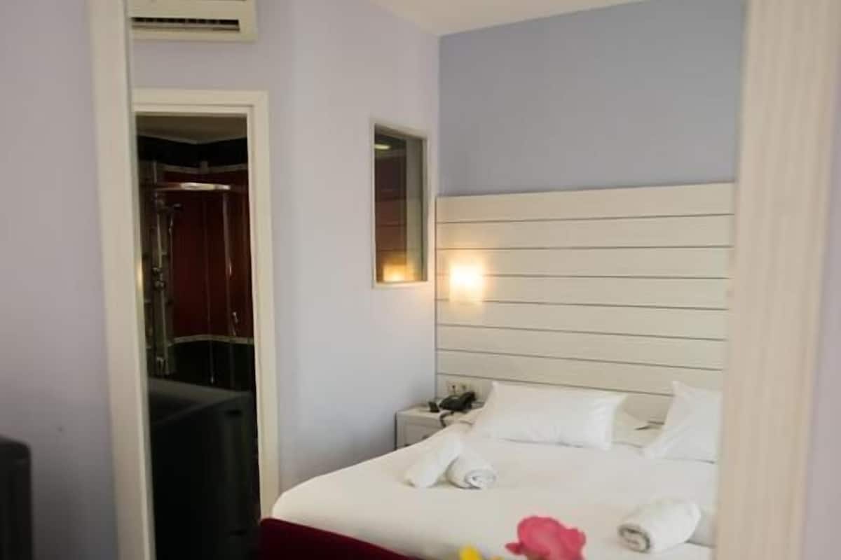 Una habitación de hotel con una cama, una mesita de noche y un espejo.