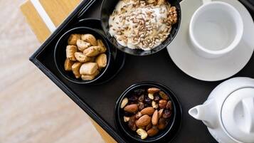 A tray with bowls of nuts, dried fruits, and cookies, a cup, and a teapot.