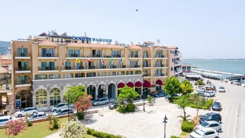 Um hotel com várias varandas, um pátio central e vista para o mar.