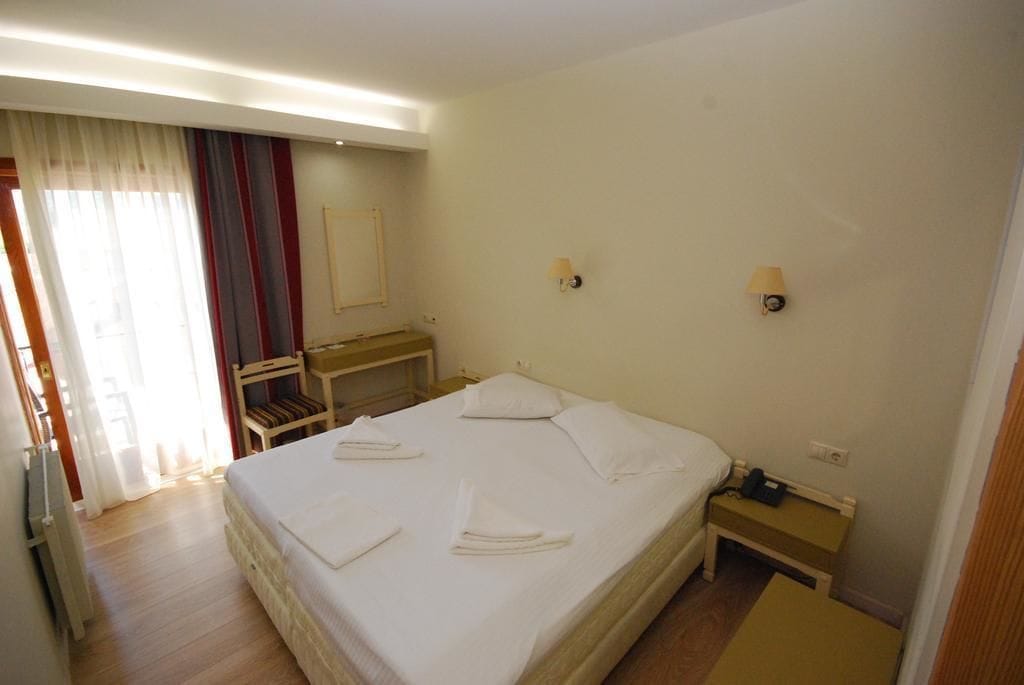 Ein Hotelzimmer mit Bett, Nachttischen, Schreibtisch und Stuhl.