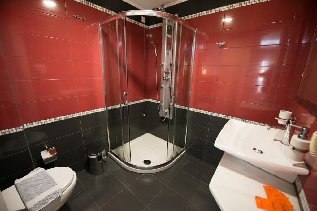 A bathroom with a glass-enclosed shower, a white sink, and a toilet.