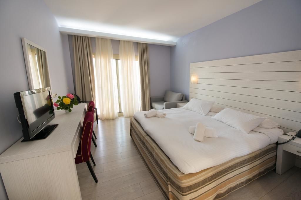 Een hotelkamer met een bed, een bureau met een televisie, een stoel en een raam met gordijnen.