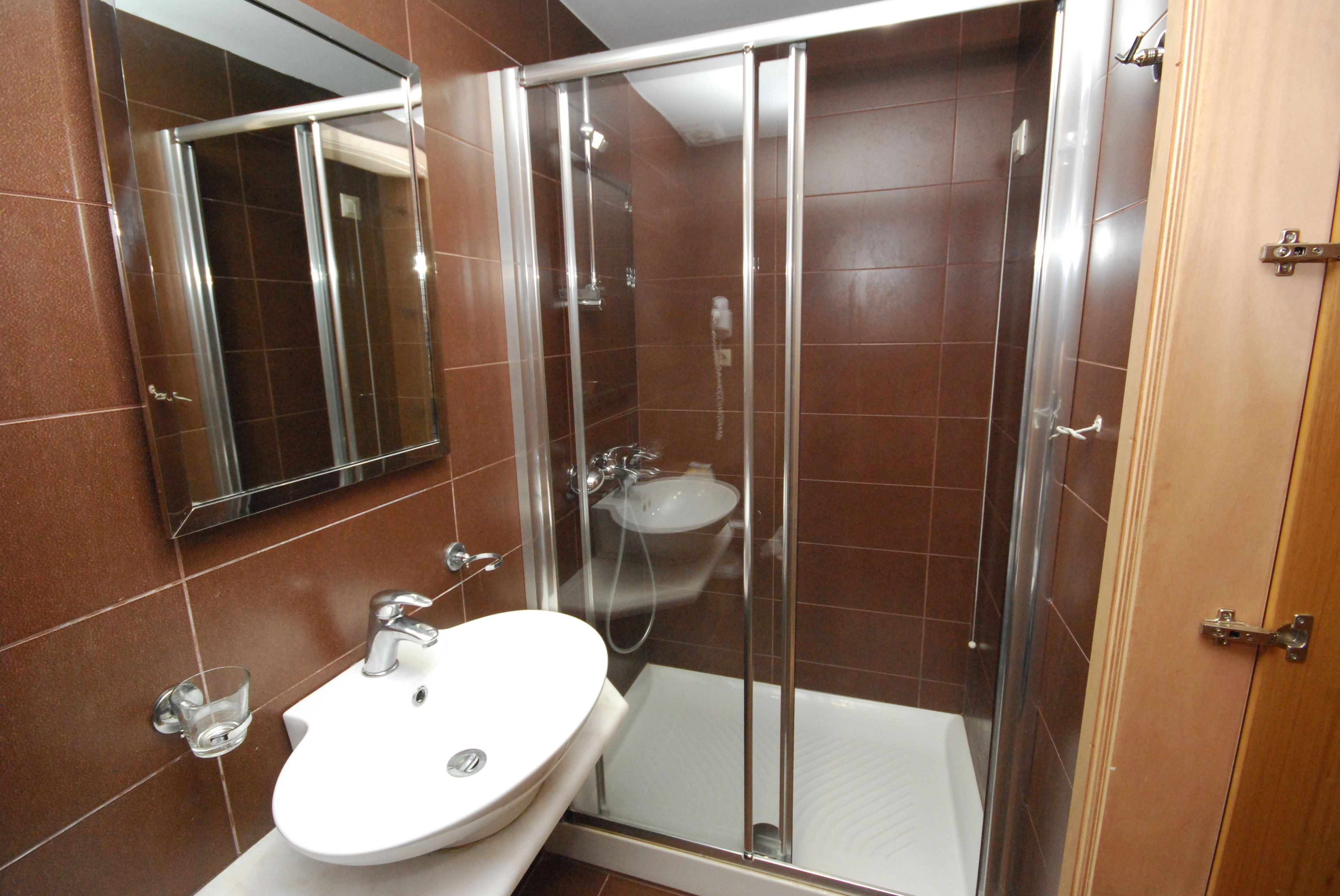 A bathroom with a glass-enclosed shower, a white sink, and a mirror.