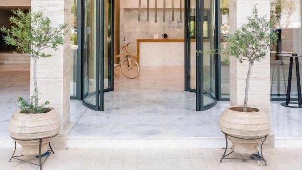 L’entrée d’un hôtel, avec une porte tournante, un comptoir de réception et deux plantes en pot.