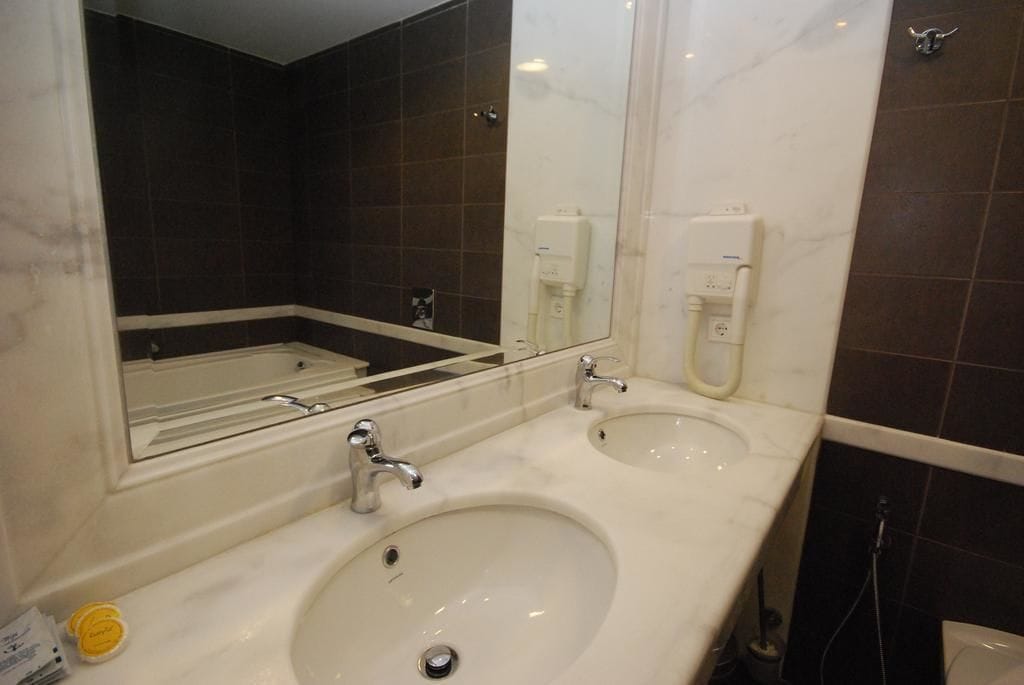 A bathroom with two sinks, a mirror, and a hand dryer.