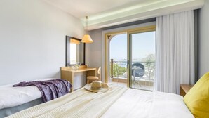 Une chambre d’hôtel avec un lit, un bureau, une chaise, une fenêtre donnant sur un beau paysage et un balcon.