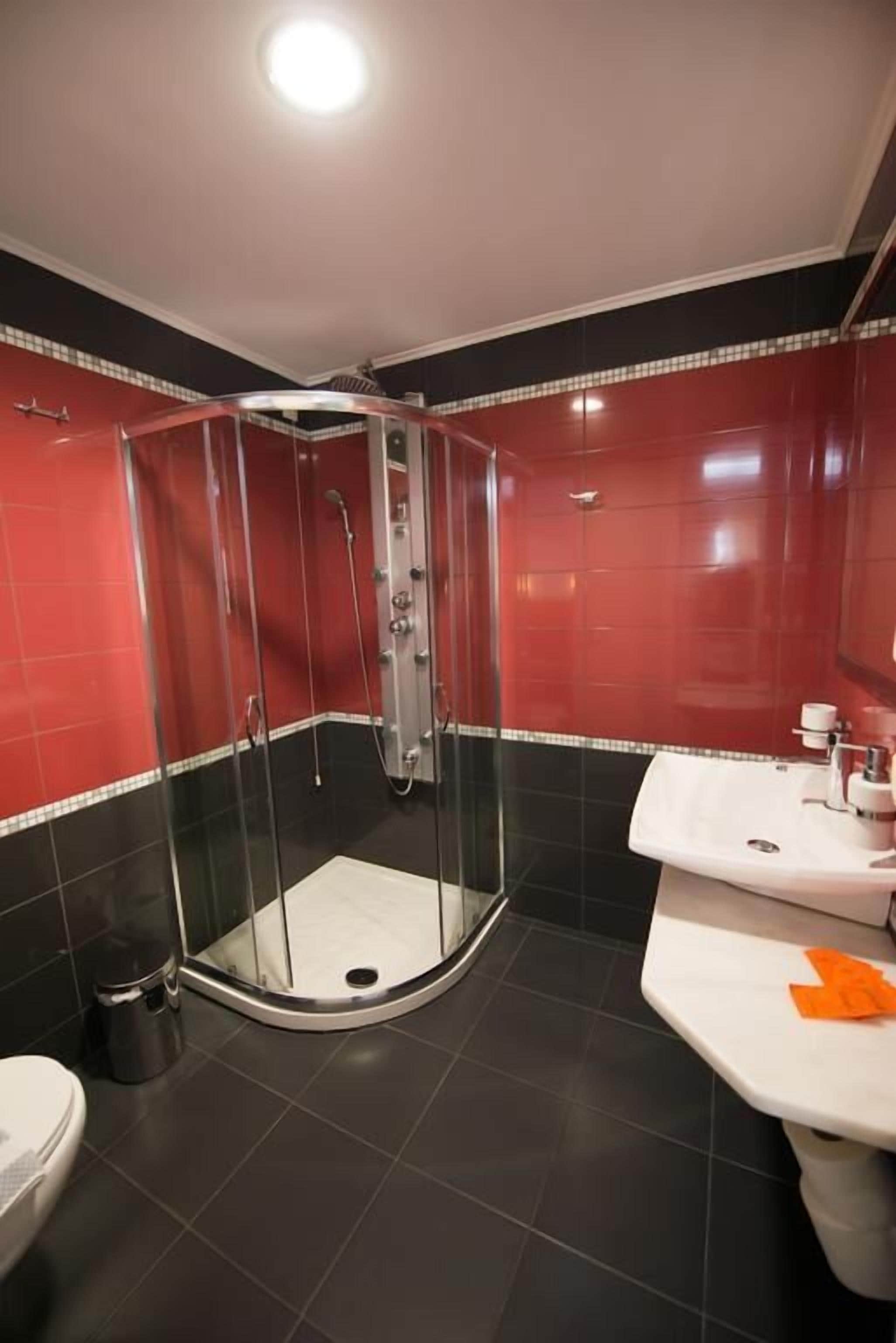 Un baño con ducha de vidrio, lavamanos blanco y un inodoro.