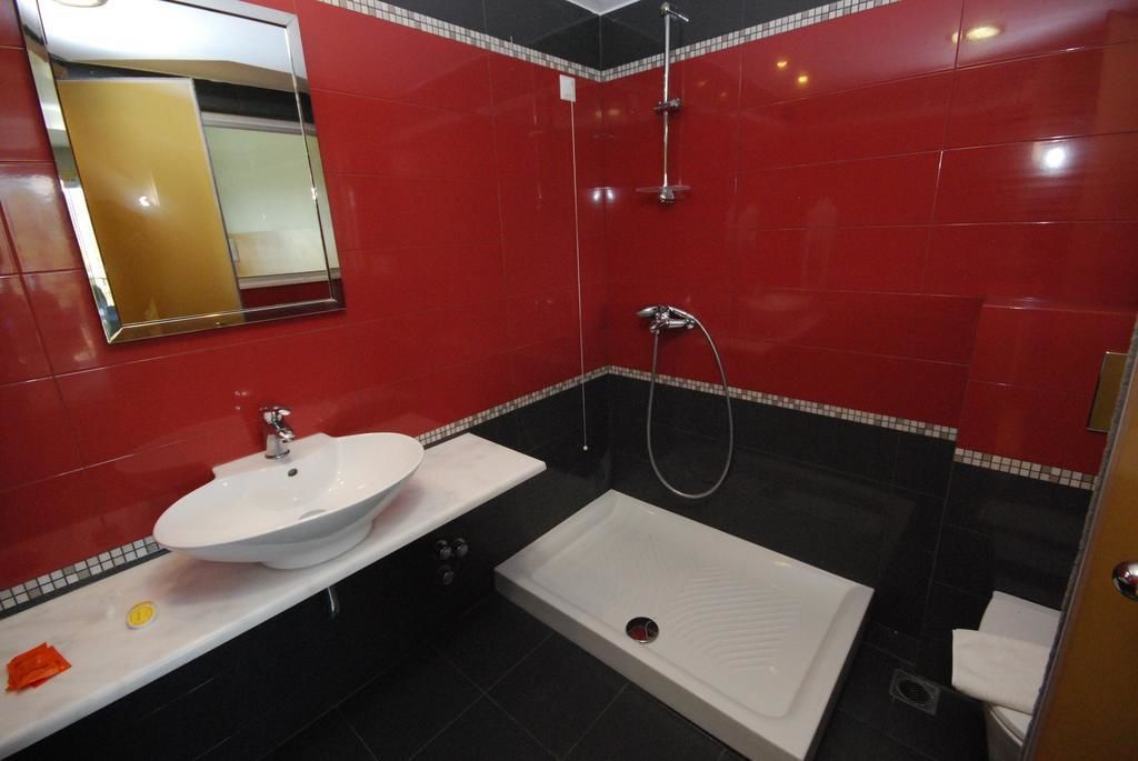 A bathroom with a white sink, a shower, and a toilet.