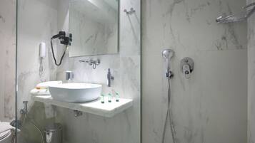 Een moderne badkamer met een marmeren wastafel, een spiegel, een handdouche en een toilet aan de muur bevestigd.