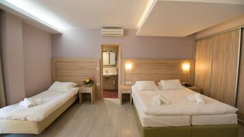 A hotel room with two single beds, a wooden headboard, a nightstand with a lamp, and a mirror.