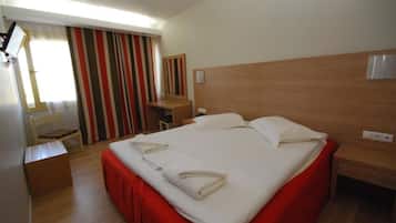 Una camera d'albergo con un letto grande, una scrivania, una sedia e una finestra con tende a righe.