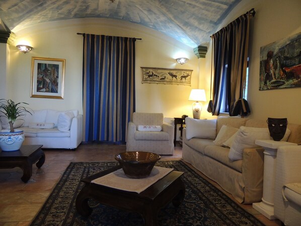 A living room with a sofa, armchairs, a coffee table, and a patterned rug.