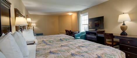 A hotel room with a large bed, two bedside tables with lamps, a desk with a chair, a television, and a window with curtains.
