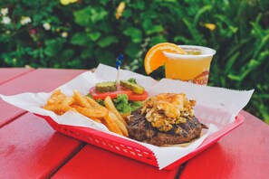 A meal consisting of a burger, fries, and a drink on a red table.