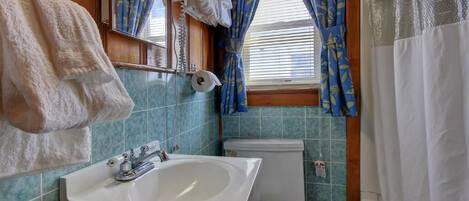 A bathroom with a sink, toilet, and shower curtain.