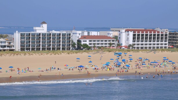 A beach resort with multiple buildings, including a hotel with a red roof and a white building with balconies.
