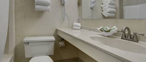 A bathroom with a toilet, sink, and two hair dryers mounted on the wall.