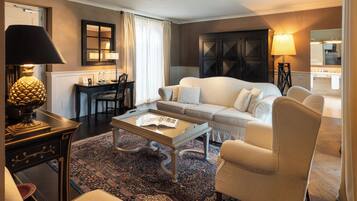 Un salón bien iluminado con un sofá, sillones, una mesa de centro y un escritorio con una lámpara.