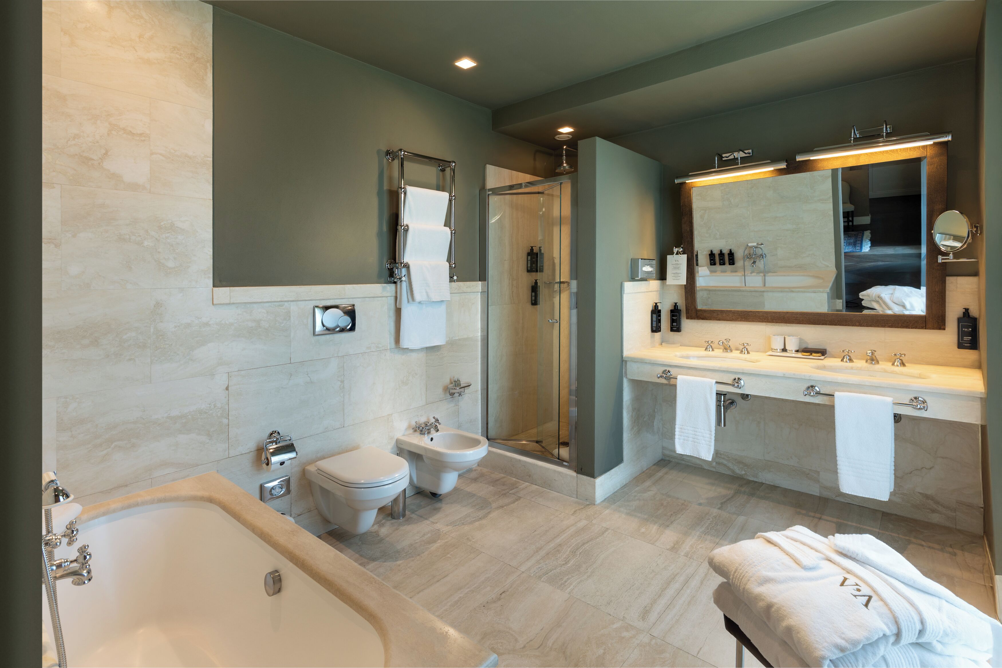 A modern bathroom with a bathtub, a shower, a bidet, and a large mirror above the sink.
