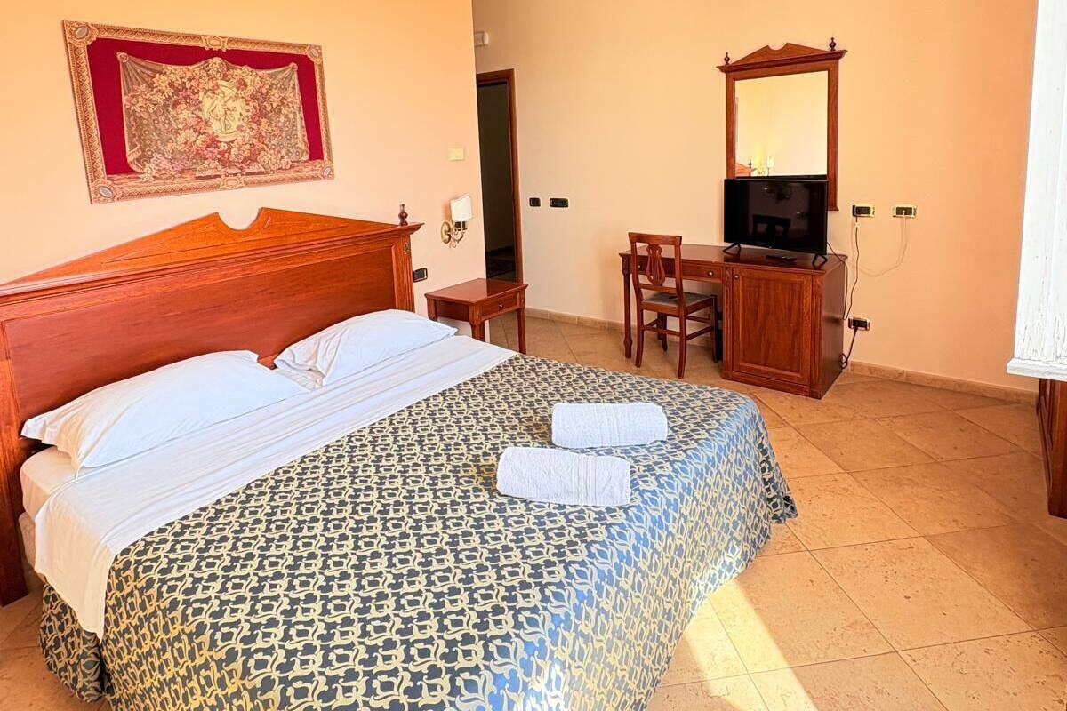 Een hotelkamer met een bed, een bureau met stoel, een televisie en een spiegel.
