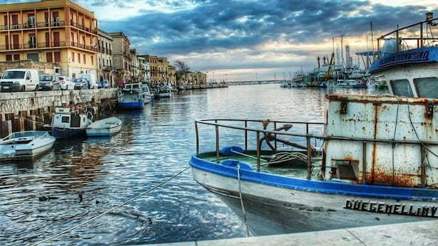 A marina with boats docked, a waterfront building, and a cloudy sky. - Hotel D'Angelo Palace (Mazara del Vallo)