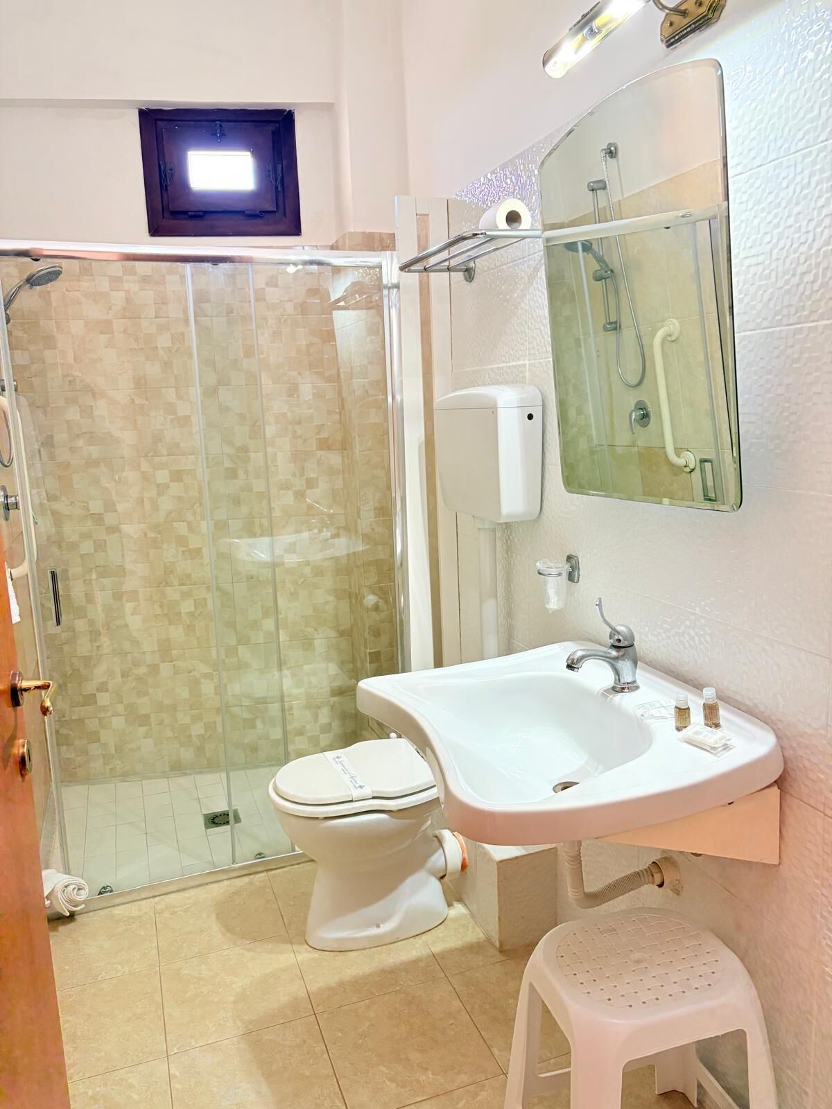 Un baño con ducha de vidrio, lavamanos blanco y retrete.