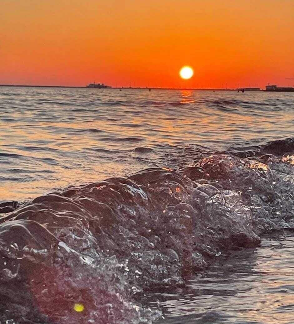 A sunset over the ocean with waves crashing onto the shore.