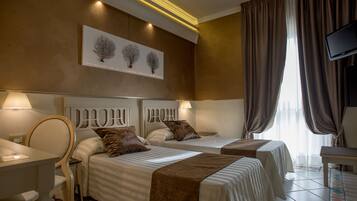 A hotel room with two beds, a desk, a chair, a TV, and a window with curtains.