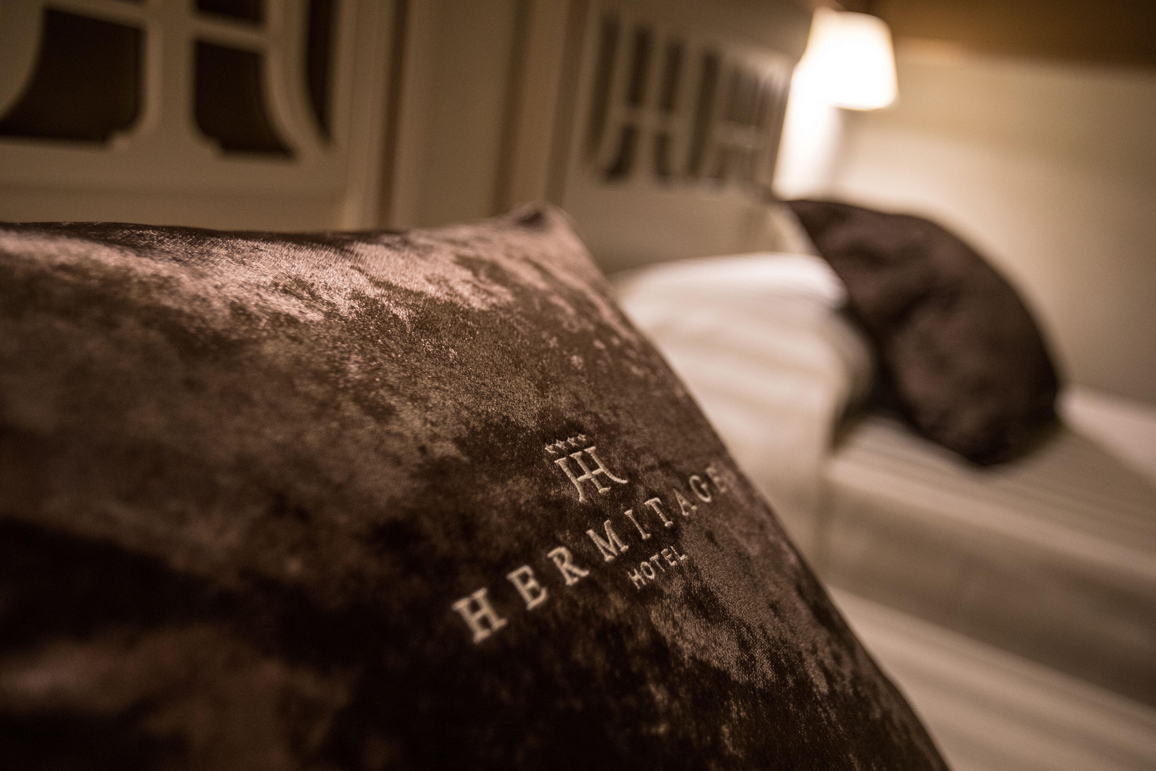 A close-up of a pillow with the inscription "Hermitage Hotel".
