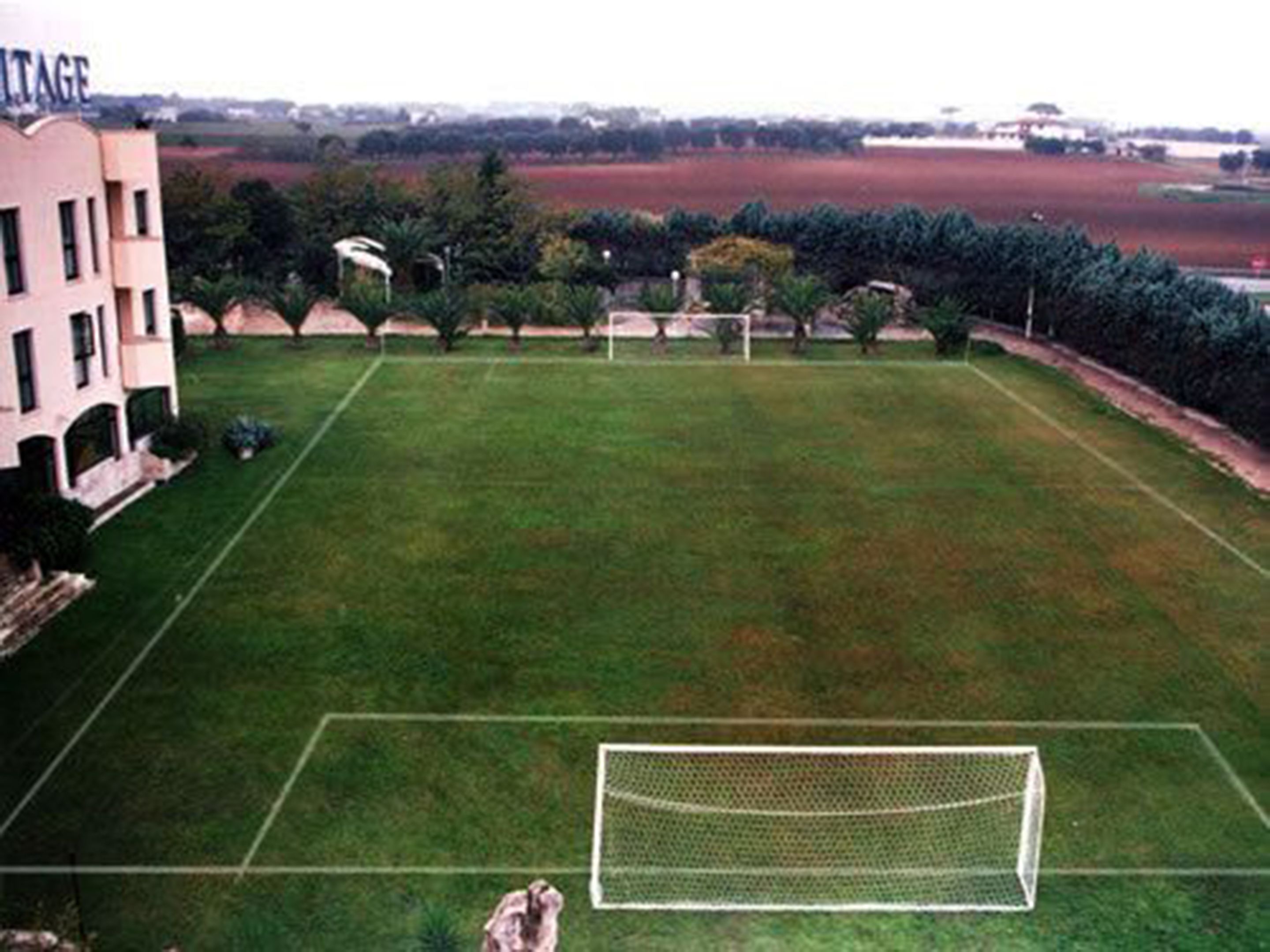 A soccer field with a goalpost, surrounded by a building with a sign that reads "VITAGE".
