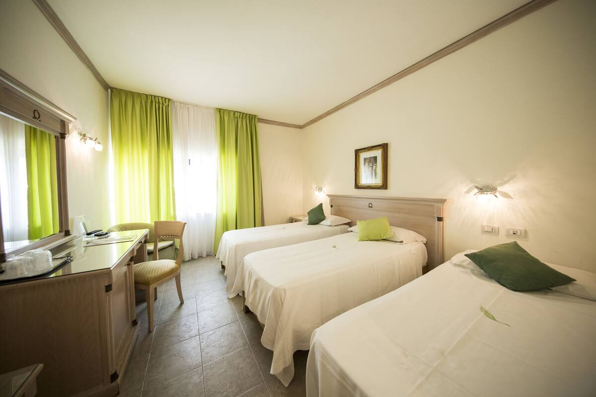 A hotel room with two single beds, a desk, and a chair.