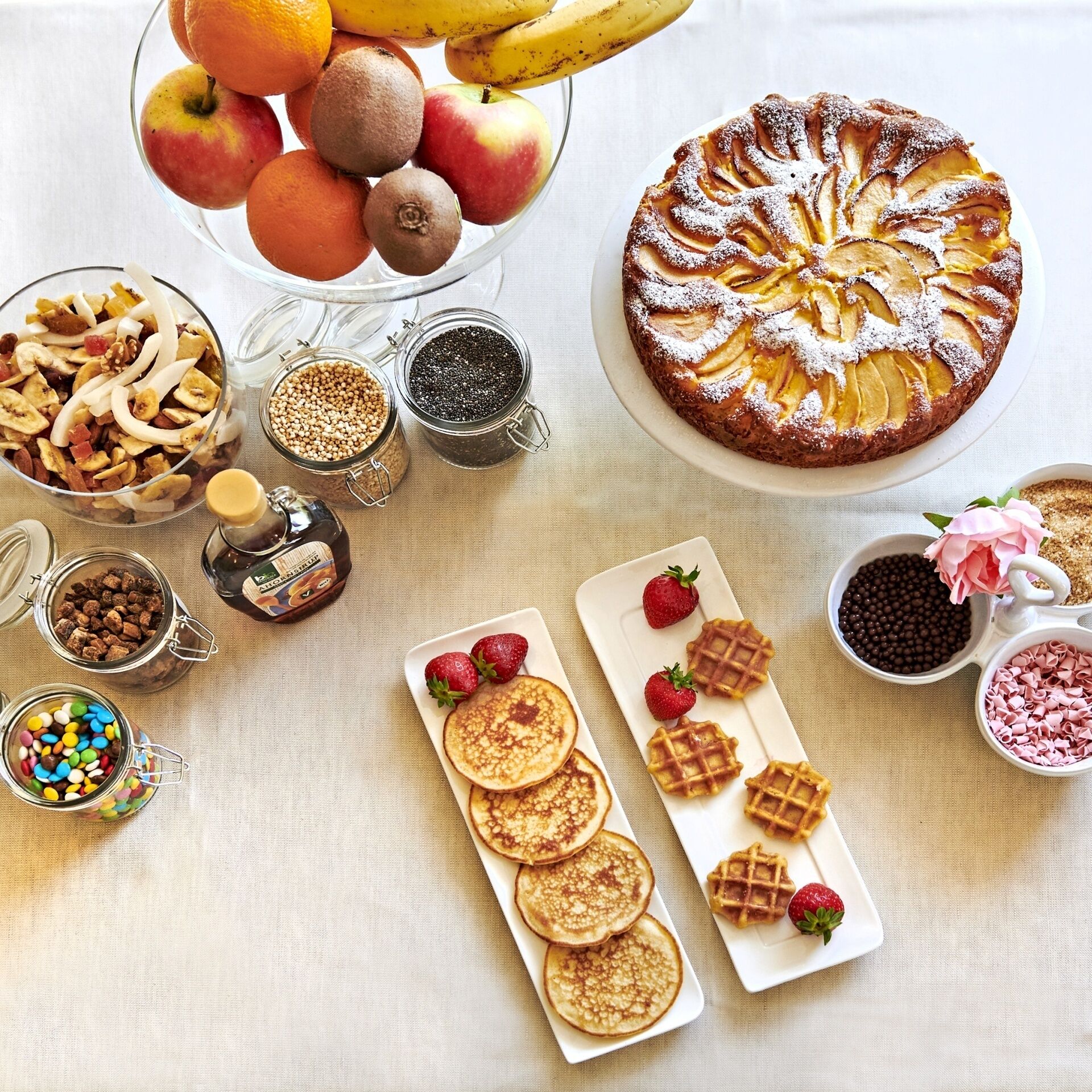 A breakfast spread with pancakes, waffles, and a fruit bowl.