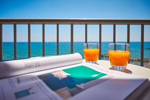 A balcony with a view of the sea, two glasses of orange juice, and a magazine. - Hotel Croce di Malta (Imperia)