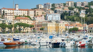 Un port de plaisance où sont amarrés de nombreux bateaux, entouré de bâtiments aux couleurs vives et dominé par un imposant beffroi.
