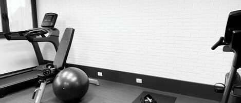 A gym with a treadmill, exercise ball, dumbbells, and a stationary bike.
