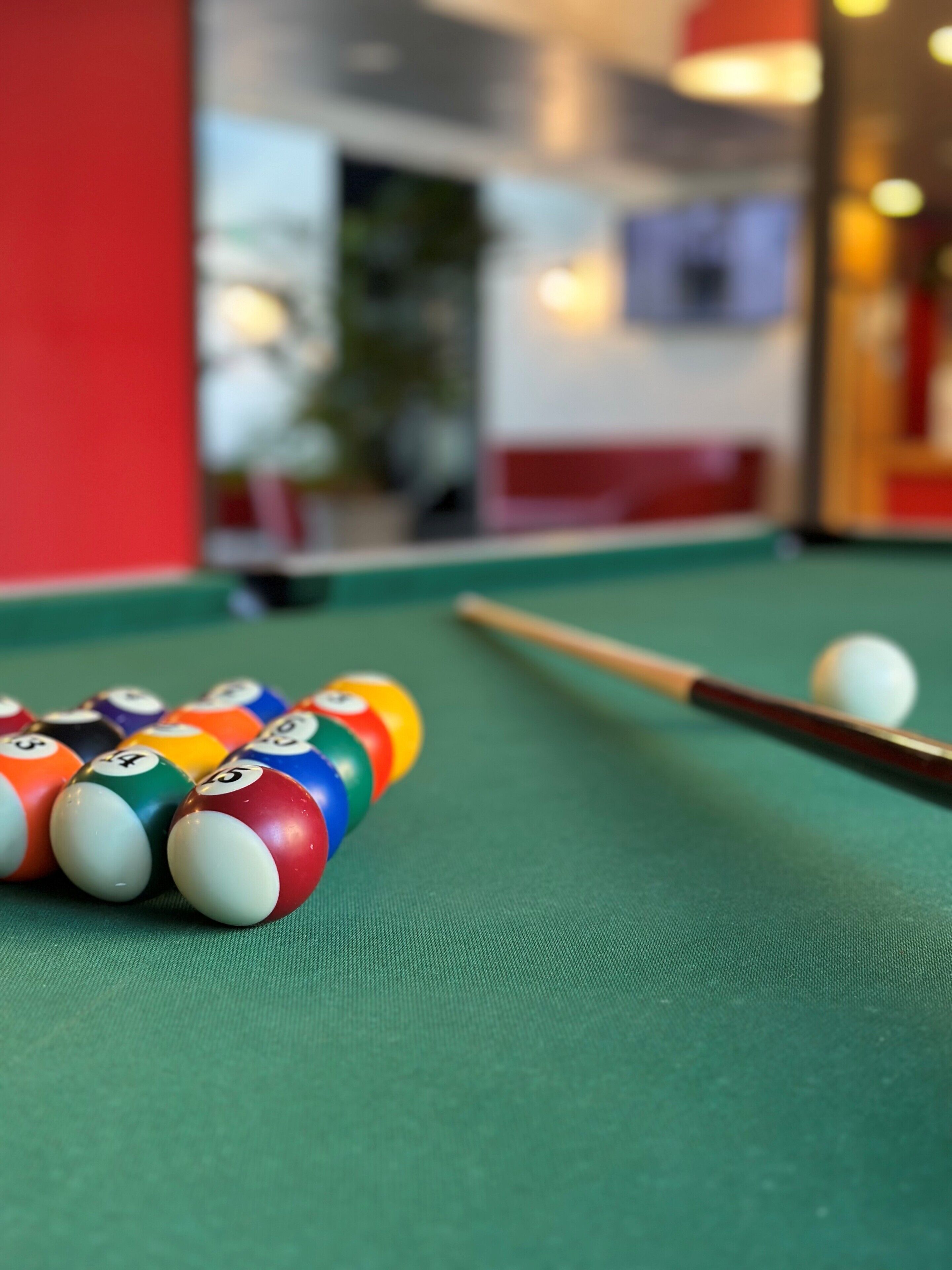 A pool table with billiard balls and a cue stick.