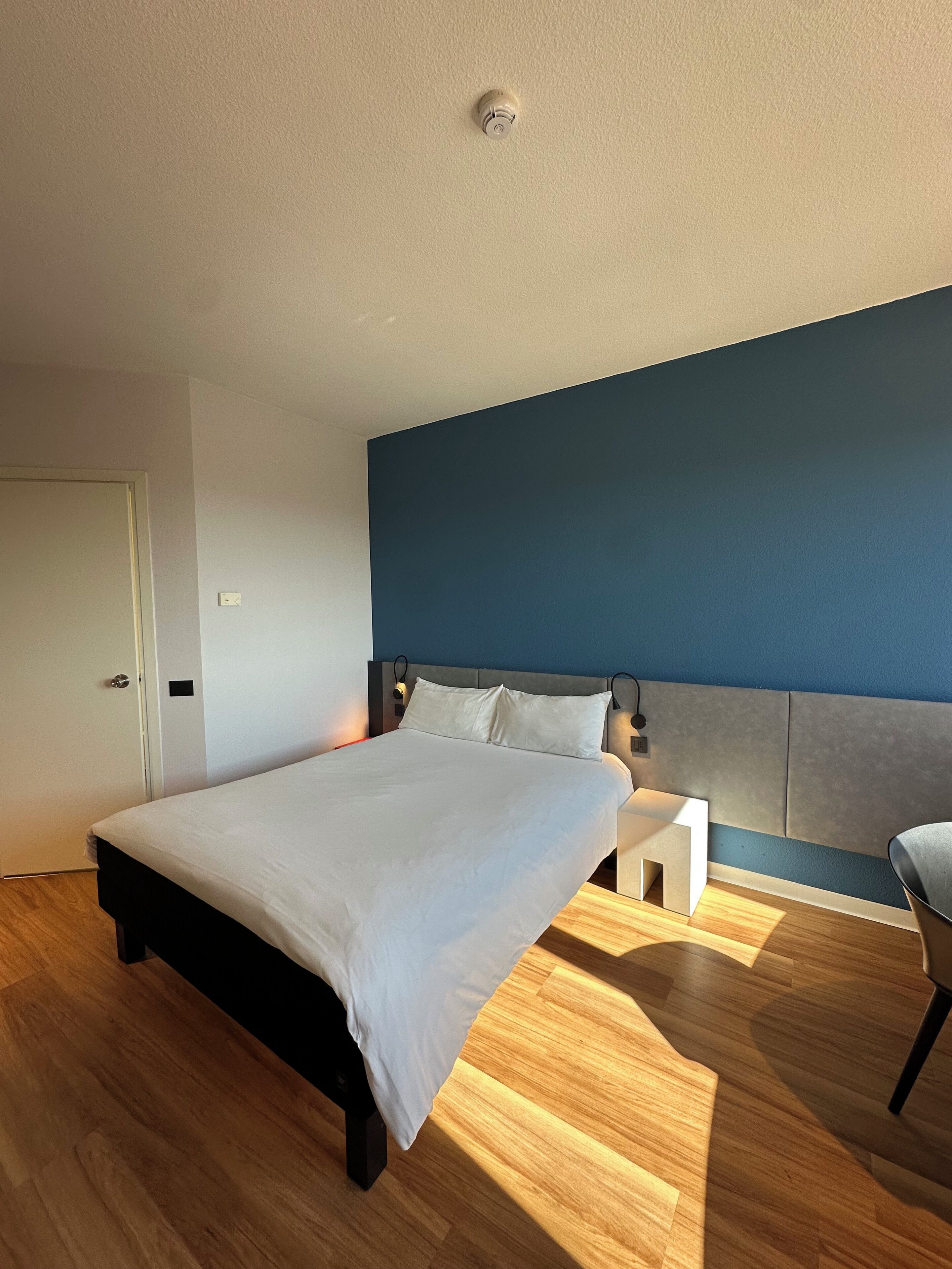 A modern bedroom with a large bed, a bedside table, and a chair.