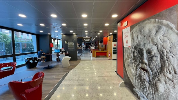 A modern interior with a reception desk, seating areas, and a large stone sculpture.