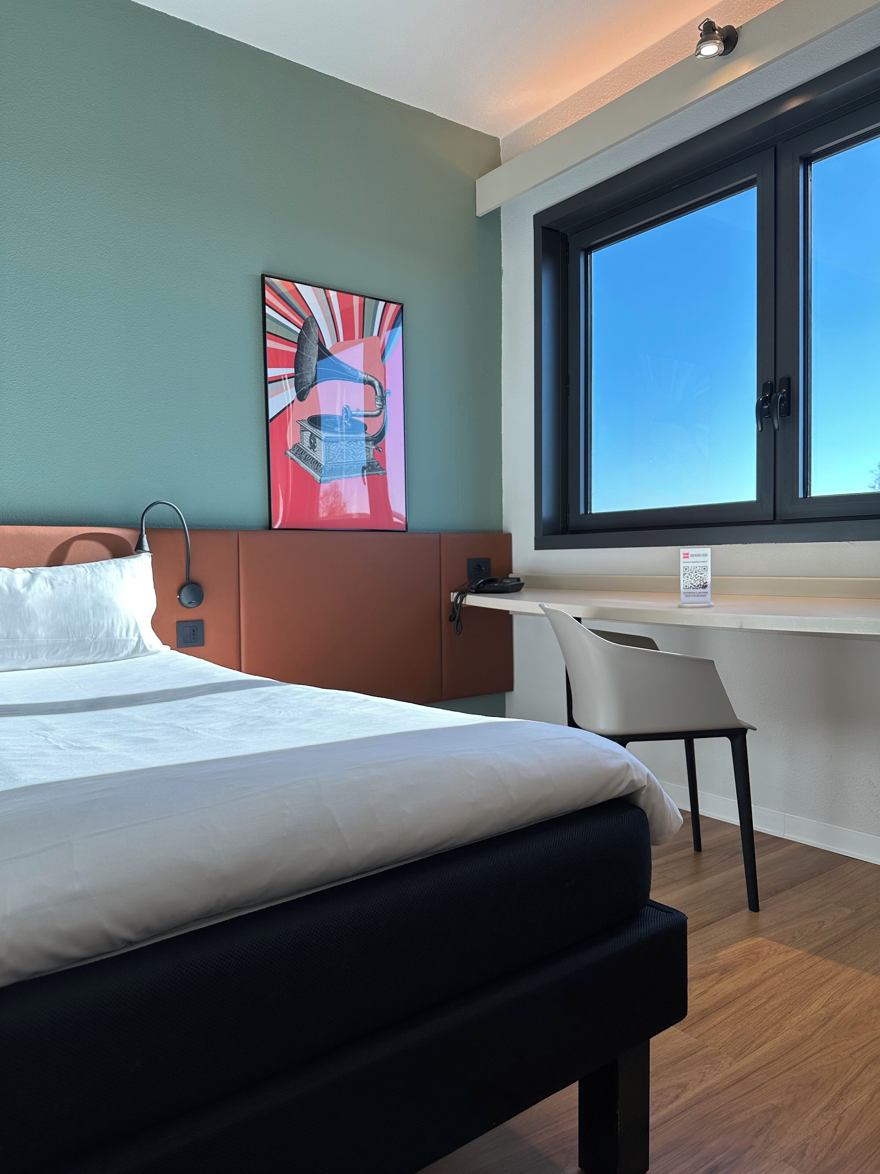 Ein modernes Hotelzimmer mit einem großen Bett, einem Schreibtisch und einem Fenster mit Blick.