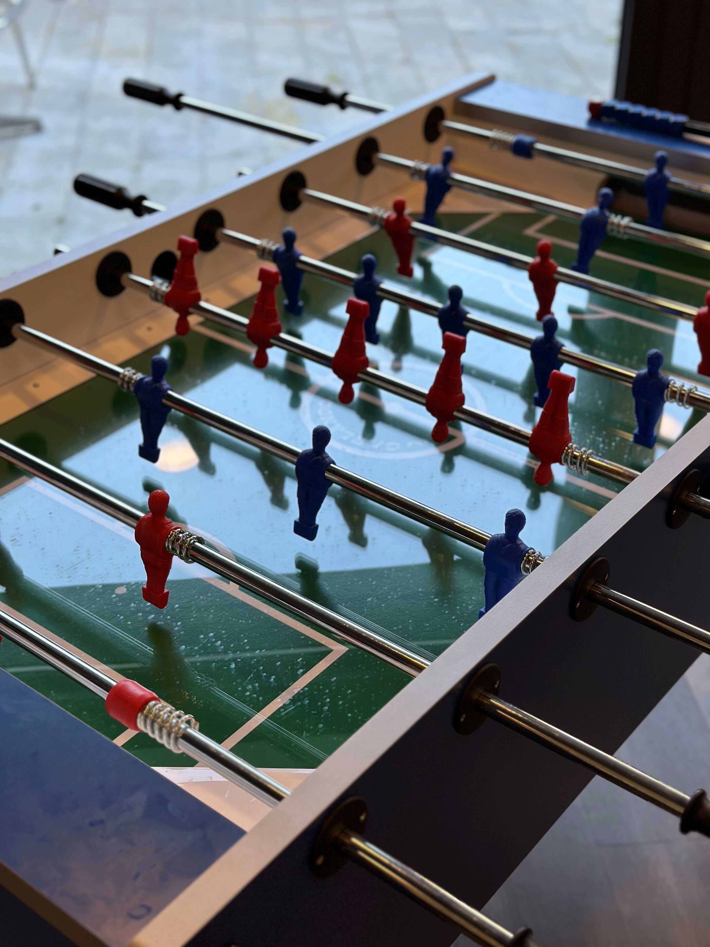 A tabletop game with a green playing surface and metal rods.