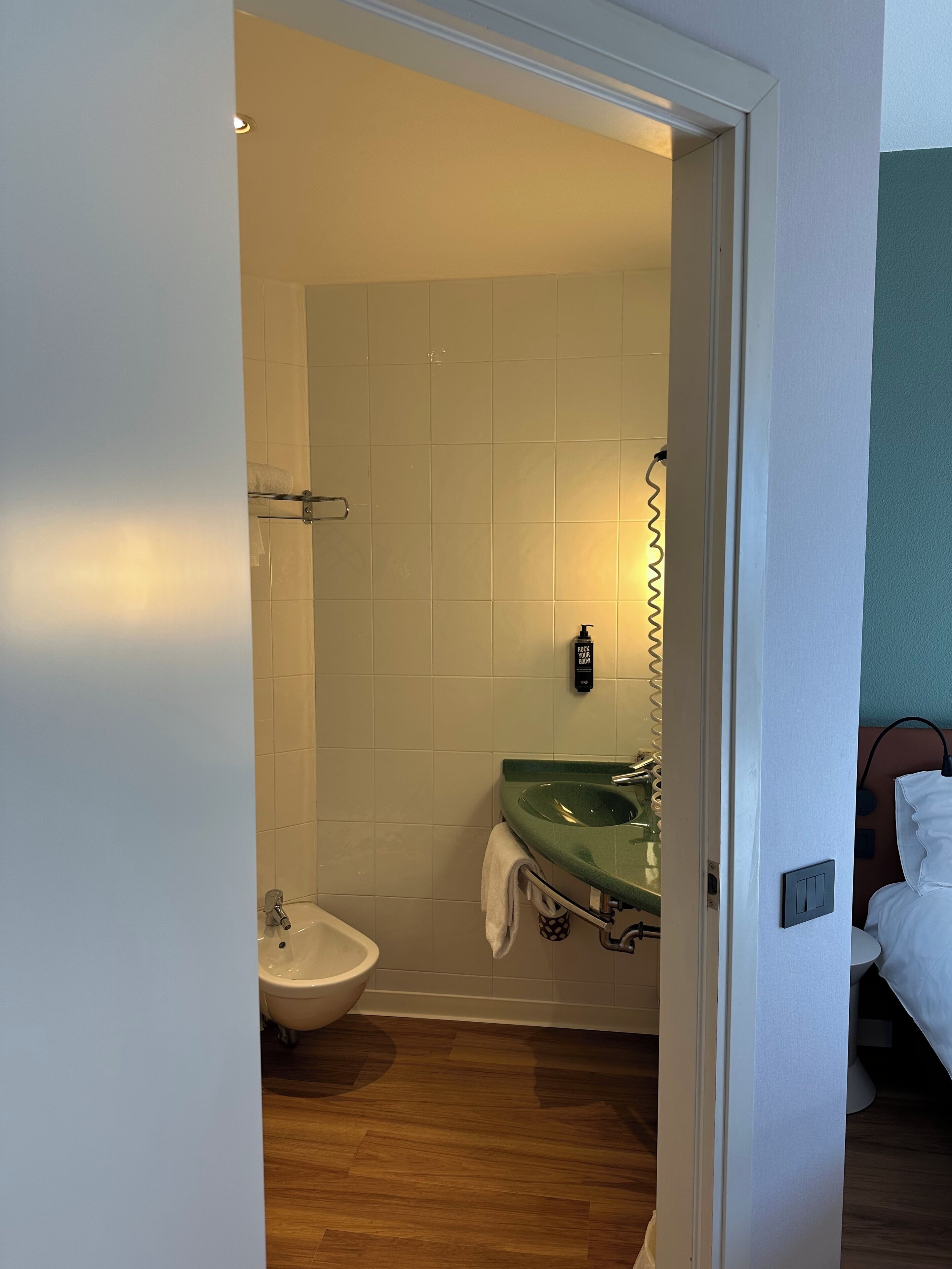 Ein Badezimmer mit einem grünen Waschbecken, einem Bidet und einer weißen Toilette.