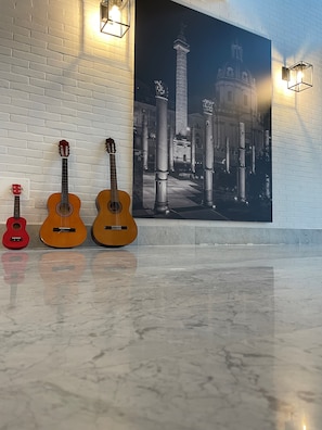 Three guitars against a white brick wall with a large black and white photograph. - ibis Roma Fiera (Rome)