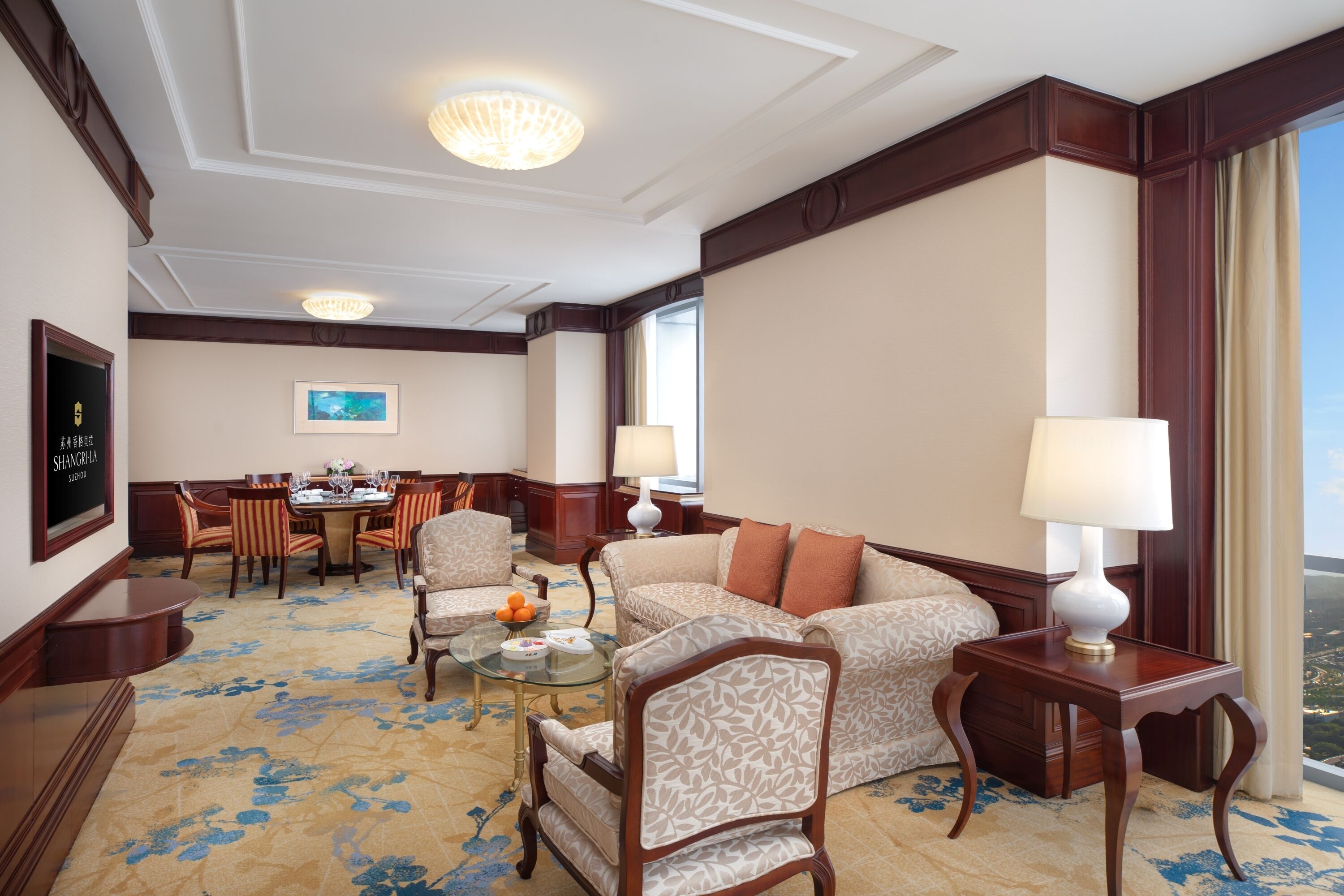 Habitación de hotel con comedor, sofá, mesa de centro y vista a la ciudad.