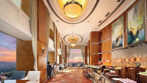 Um saguão de hotel com vista para a cidade, um balcão de recepção e um espaço para buffet.
