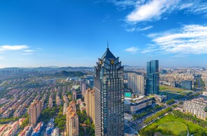 A high-rise building with a unique architectural design, surrounded by other high-rise buildings and a cityscape. - Shangri-La Suzhou (Suzhou)