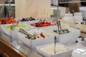 A buffet with various food options including salads, fruits, and cheeses.