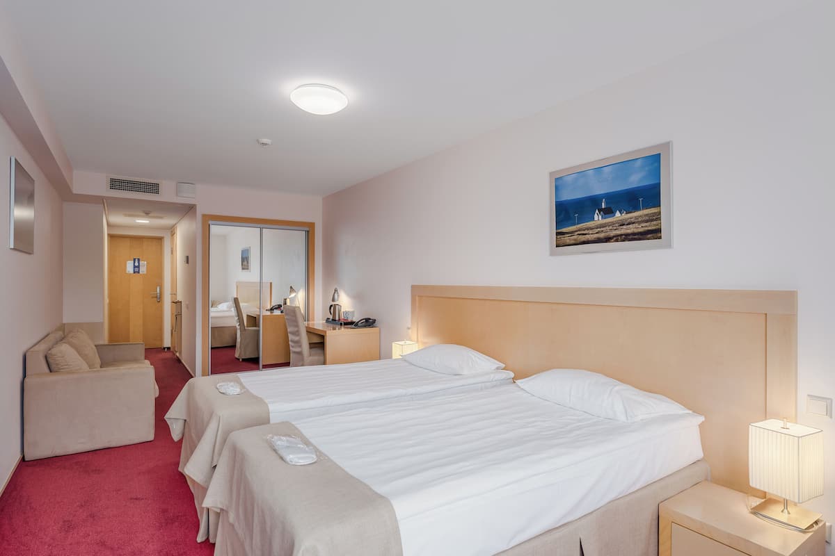 Ein Hotelzimmer mit einem großen Bett, einem Schreibtisch, einem Stuhl und einem kleinen Tisch.